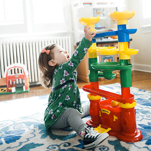 Little girl playing with Discovery Toys' Castle Marbleworks Marble Run<br>